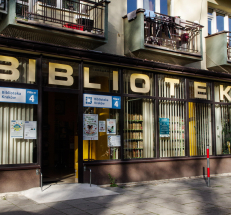 Na zdjęciu siedziba Filii nr 4. Znajduje się ona na parterze, przed wejściem niewielki podjazd bezpośrednio z chodnika. Nad wejściem duży napis „BIBLIOTEKA”. Po prawej i lewej stronie drzwi szklane witryny, na nich tabliczki z oznaczeniem filii.